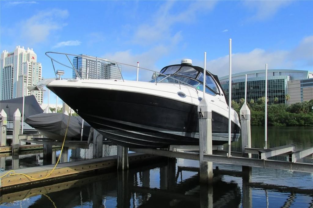 Large cabin cruiser on motorized boat lift at Crimson Harbour Marina Tampa FL — JW Marriott and Amalie Arena in background